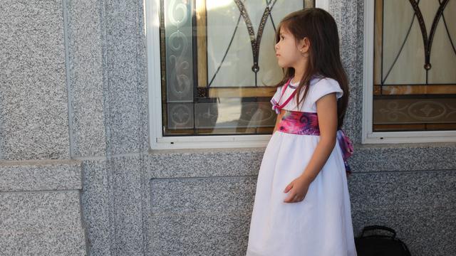 Une petite fille attend la visite de Président Uchtdorf et d'Elder Christofferson avant la cérémonie de la pierre d'angle.