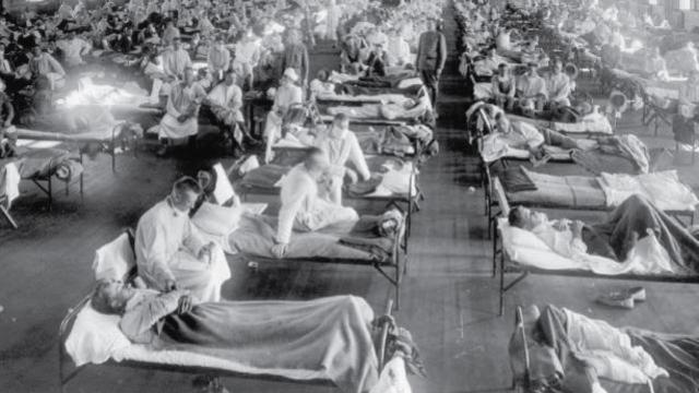 Des lits de campagne avec des patients dans une grande sale, au cours de la Première Guerre Mondiale.